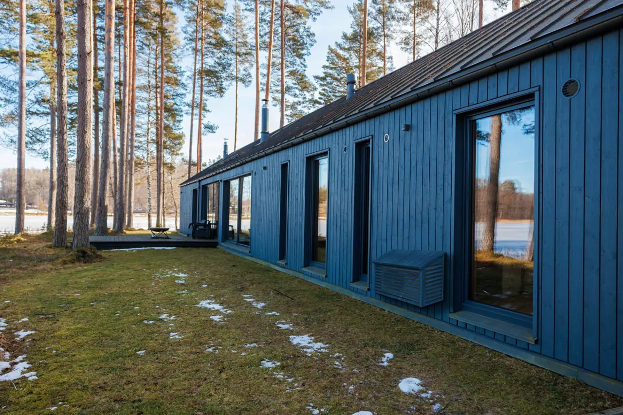 Sortbeiset varmepumpehus i tre, går i ett med en mørk fasade.